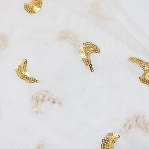 Close-up of sheer mesh fabric featuring decorative golden sequin crescent moon patterns