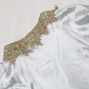 Detail of ice blue satin dress featuring intricate gold lace embroidery on the neckline