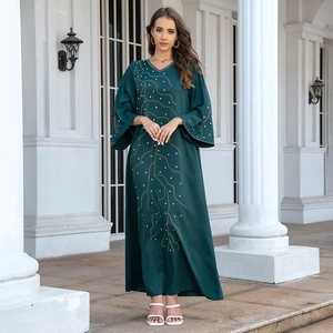 Détail de la robe abaya vert foncé avec col en V, broderie dorée et perles blanches