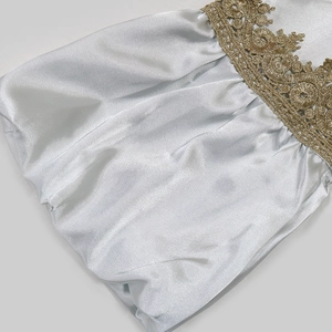 Close-up of lantern sleeve dress featuring golden floral lace embroidery on satin fabric