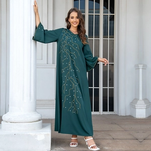 Détail de la robe abaya ample vert foncé avec broderies dorées et manches évasées larges