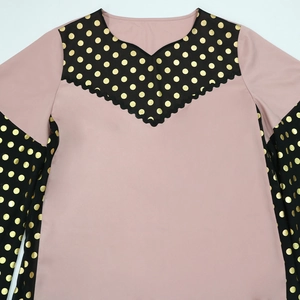 Detail of V-neck stitching with scalloped edges and gold polka dots on lotus pink fabric