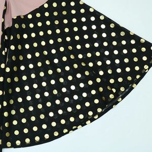 Detail of black fabric with golden metallic dots and pink patchwork stitching