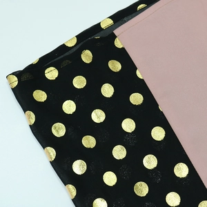 Detailed macro view of black fabric with gold metallic polka dots and pink patchwork