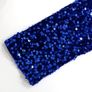 Detail of royal blue velvet fabric adorned with shimmering metallic sequins and texture