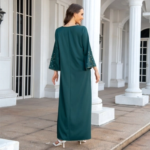 Détail des manches évasées avec perles dorées et paillettes sur une robe longue vert foncé