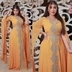 Detail of yellow kaftan featuring gold embroidery, belt, and elegant cape sleeves