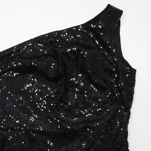 Dettaglio di paillettes nere e texture di nappe su un abito da sera monospalla