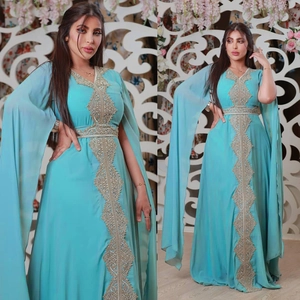 Detail of teal chiffon kaftan with intricate gold beadwork embroidery and cape sleeves