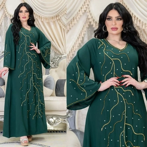 Détail de l'abaya vert foncé avec broderie de perles dorées et accents de perles blanches