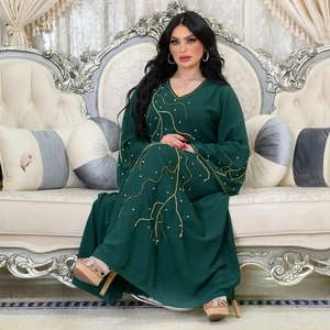 Détail d'une robe Abaya ample vert foncé avec broderie dorée et ornements en strass
