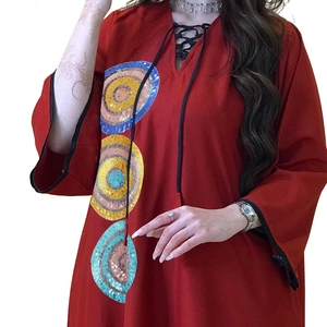 Detail of dark red kaftan dress featuring colorful sequin concentric circles and V-neck tie