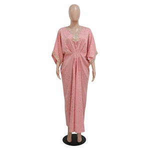 Dettaglio dello scollo a V con paillettes dorate e trama del tessuto kaftan rosa a pois