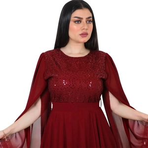 Detail of wine red sequined evening gown featuring split cape sleeves and pleated skirt