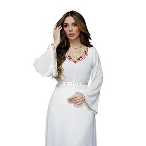 Détail d'une robe en mousseline blanche avec broderie de perles multicolores et ceinture fine