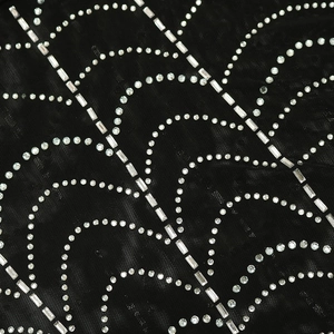 Close-up of sparkling rhinestones on black mesh fabric of a sexy party dress