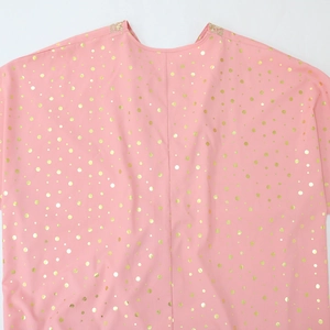 Dettaglio del tessuto kaftan rosa con pois dorati e raffinato ricamo floreale sul bordo