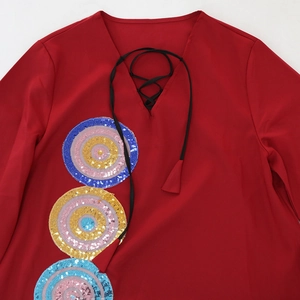 Close-up of deep V-neckline with black drawstrings and colorful sequin embroidery