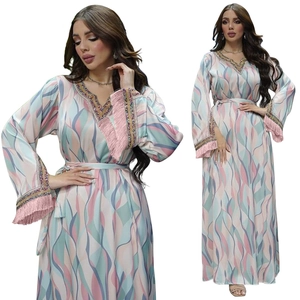 Close-up of V-neckline with gold braid trim and pink tassel sleeve details on kaftan dress