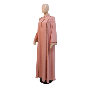 Détail du jalabiya rose montrant les broderies perlées dorées et rouges sur le devant