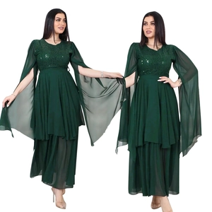 Detail of elegant emerald green evening dress with sequined bodice and flowing cape sleeves
