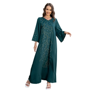 Détail de caftan vert foncé avec broderie dorée en forme de branche et strass