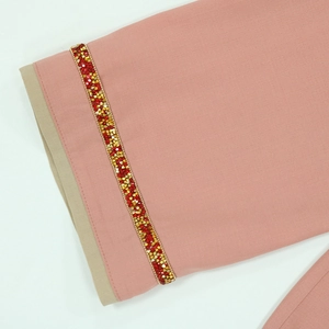 Détail macro de la manche jalabiya rose avec embellissements de strass rouges et ors