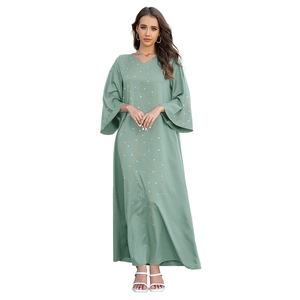 Détail de robe caftan vert sauge avec broderie dorée et ornements en strass