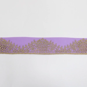 Detail of elegant purple chiffon fabric with golden lace embroidery and wavy patterns