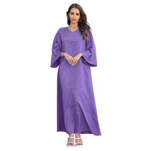 Détails de broderie dorée et paillettes blanches sur une robe longue violette ample