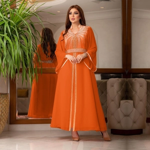 Close-up of intricate gold and silver rhinestone embroidery on an orange chiffon kaftan dress