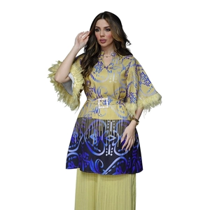 Detail eines gelben Boho-Kaftans mit Feder-Ärmelmanschetten und quadratischer Gürtelschnalle