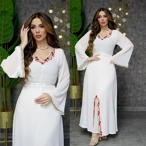 Détail de la robe en mousseline blanche avec broderie florale rouge et dorée et col en V