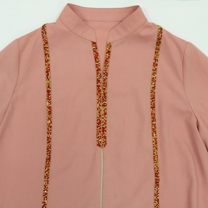 Détails de l'encolure perlée et des paillettes sur cette robe jalabiya rose