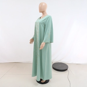 Détail de la robe longue vert clair avec perles dorées et strass blancs brillants