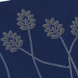 Close-up of leaf pattern rhinestones on dark blue fabric with gold and white crystals