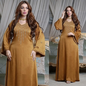 Amber yellow Kaftan dress with flared sleeves and sequin V-neckline in indoor setting