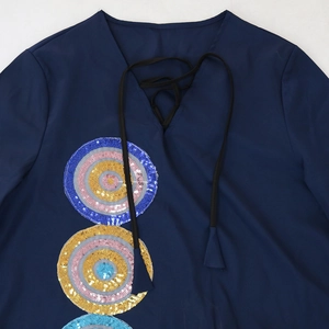 Close-up of V-neckline with black lace-up ties and colorful sequin embroidery on blue dress