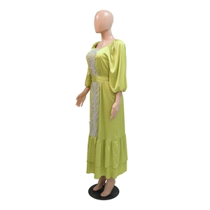 Detail of light green kaftan dress with white lace embroidery and ruffle hem