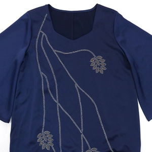 Detailed view of rhinestone leaf pattern and beaded V-neckline on navy blue dress