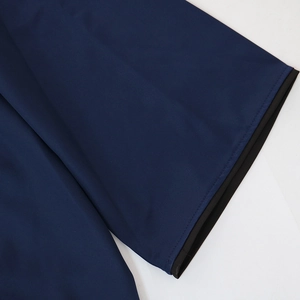 Detailed view of the navy blue dress fabric featuring black contrast trim and fine stitching