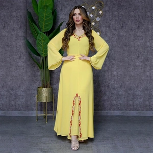 Détails de broderie florale rouge et blanche sur une robe en mousseline jaune