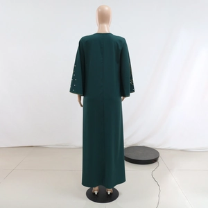 Détail du dos de la robe longue vert foncé avec des strass sur les manches larges
