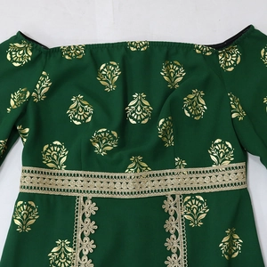 Detail of emerald green off-shoulder dress with golden floral print and lace trim