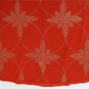 Detail von rotem Chiffonstoff mit goldenen Strasssteinen im Schneeflockenmuster