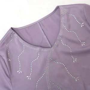 Close-up of sparkling rhinestone embellishments on a purple V-neck long dress collar