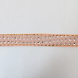 Macro shot of pink fabric trim with sparkling rows of gold and white rhinestones