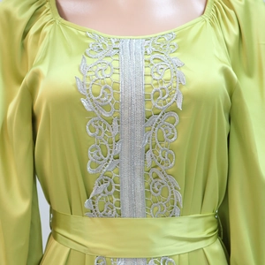 Detail of lime green satin dress featuring intricate silver lace embroidery and puffed sleeves