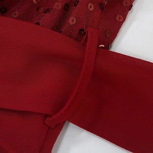 Detail of dark red sequin mesh fabric with refined stitching on the belt loop