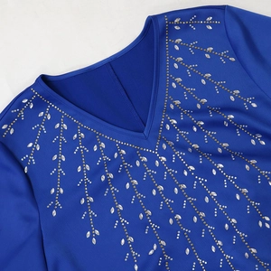 Detailed close-up of V-neckline with intricate gold rhinestone embroidery on blue fabric